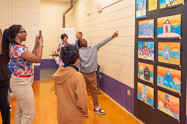 A student proudly points out their artwork.